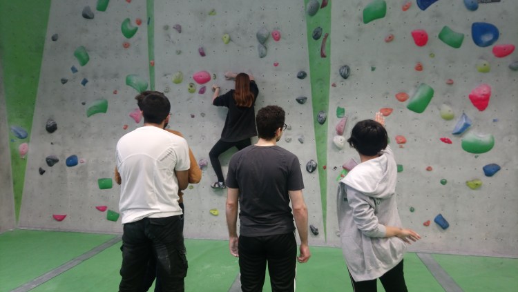 People watching a woman climb a wall